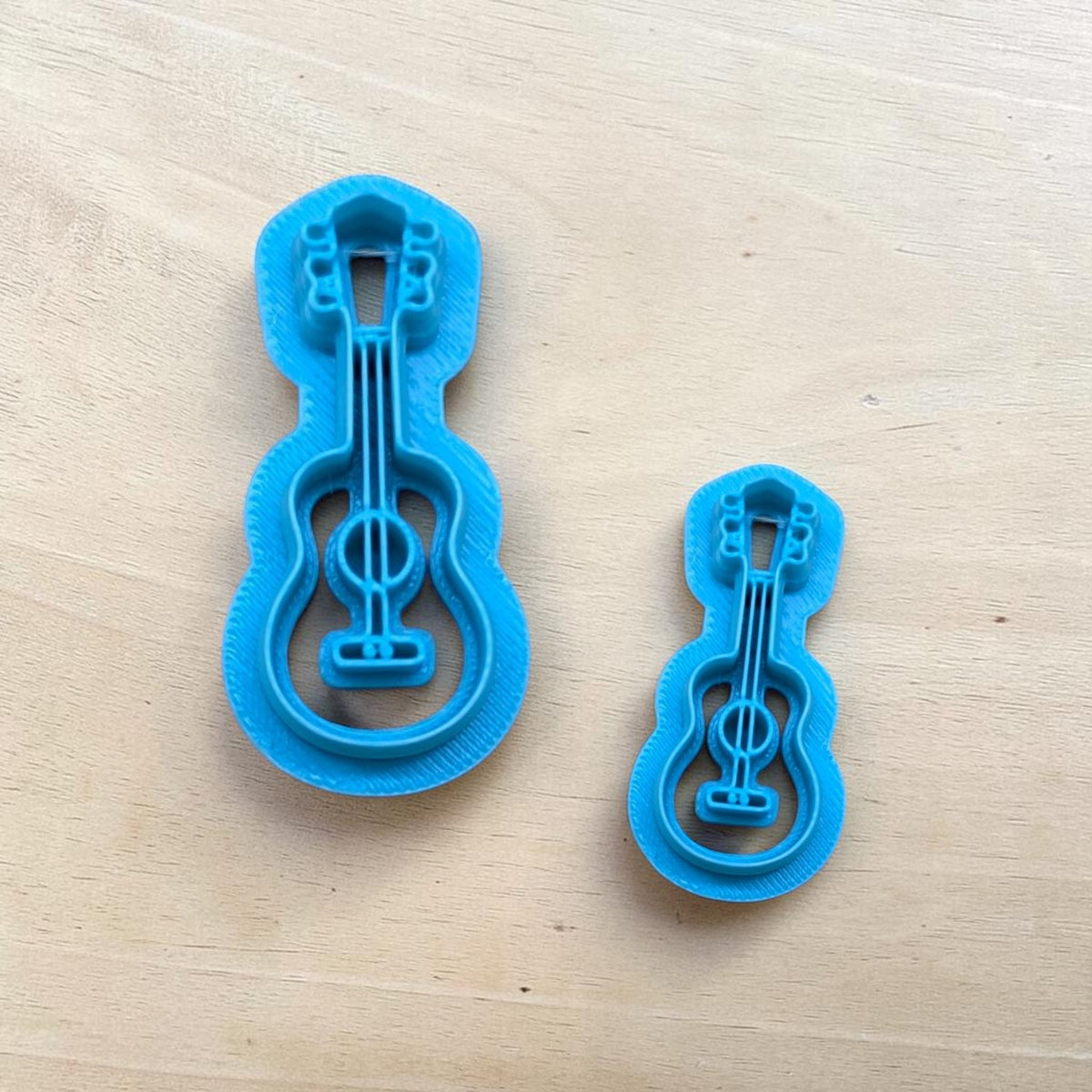 Set of two blue acoustic guitar cookie cutters in different sizes for polymer clay, fondant, pottery, and ceramic crafting.