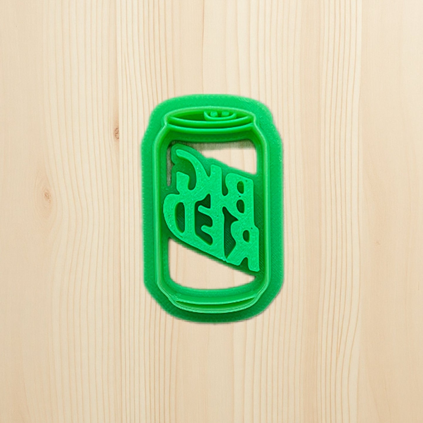 Plastic green Mountain Dew soda pop can shape cookie cutter on a wooden surface