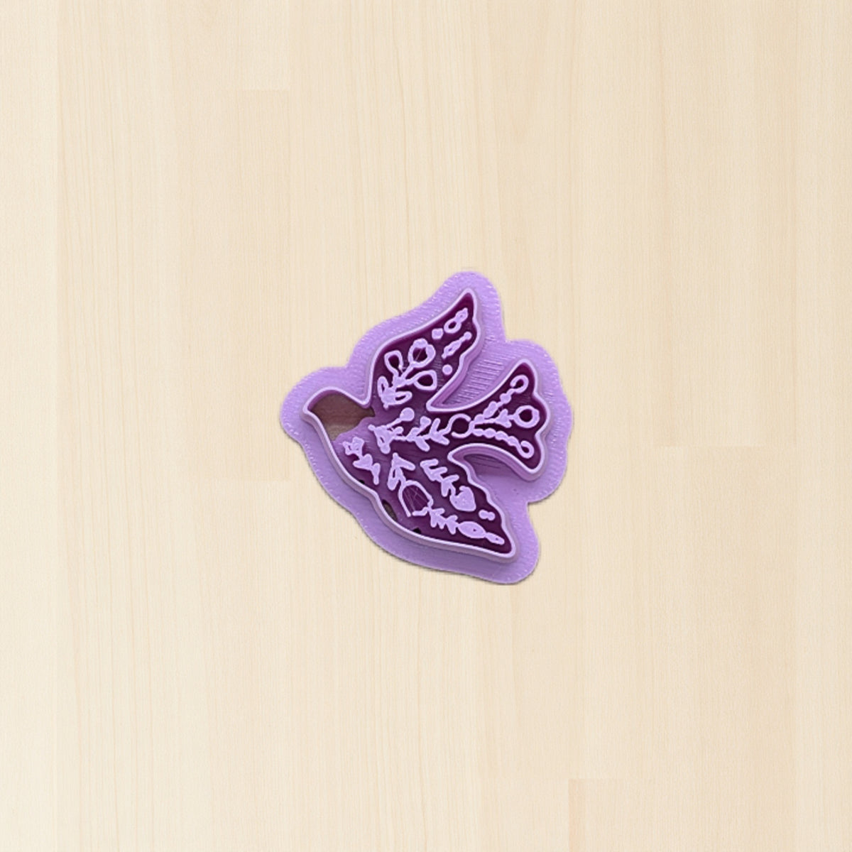 Boho folk art bird cookie cutter on wood surface.