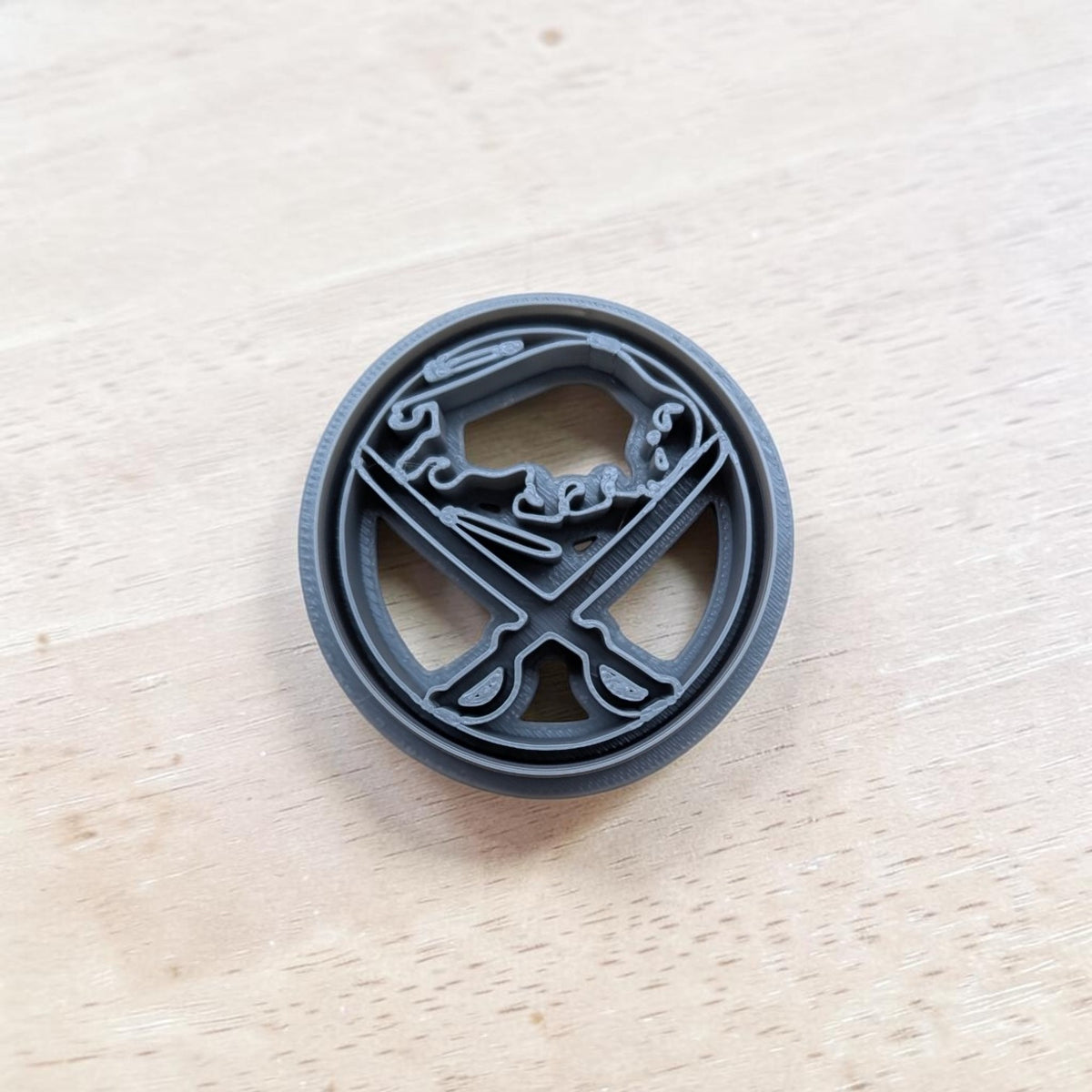 A plastic blue Buffalo Sabres cookie cutter design, resting on a light-colored wooden surface.