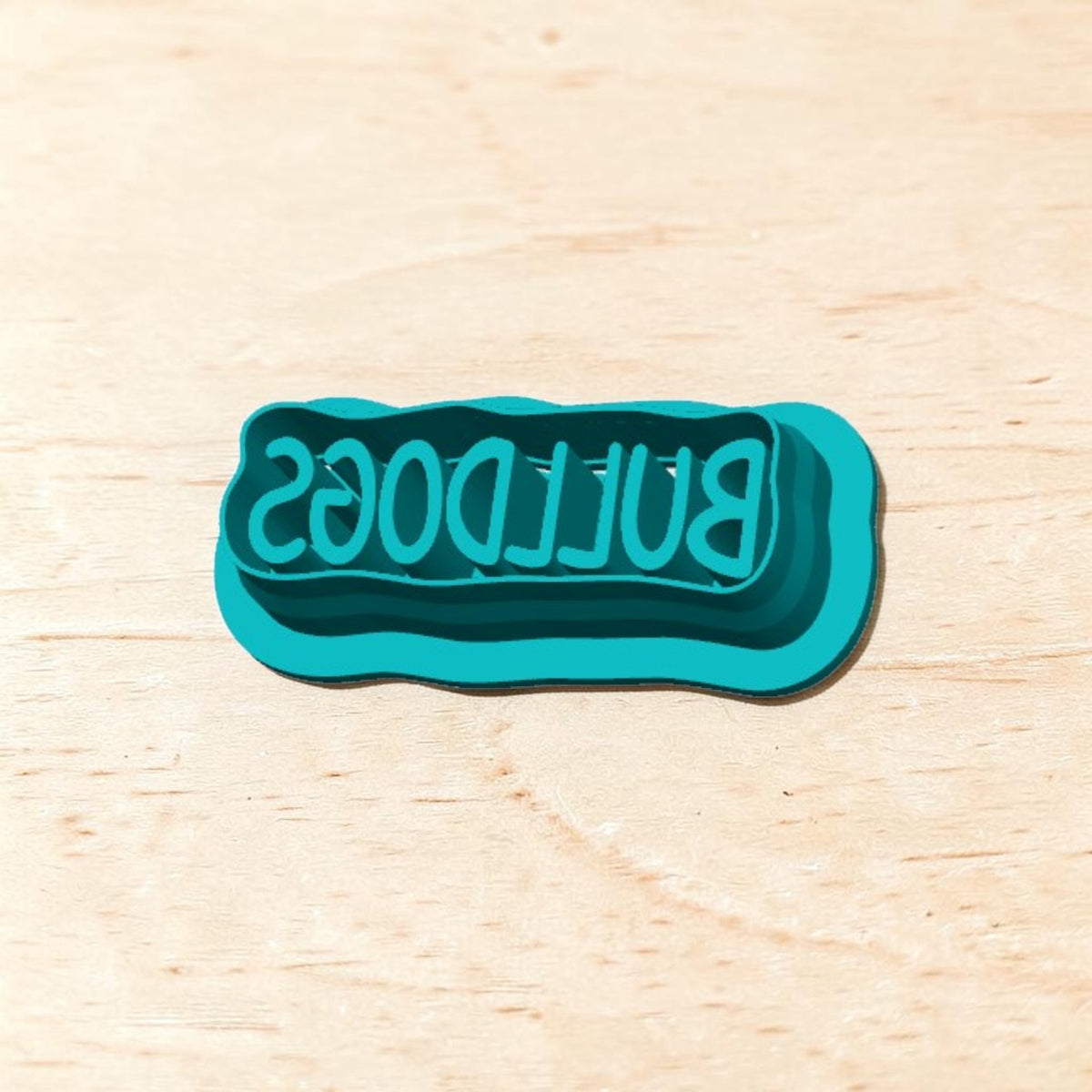 Teal Bulldogs rectangle cookie cutter text design on a light wooden background, ideal for school spirit cookies, fondant, or clay crafts.