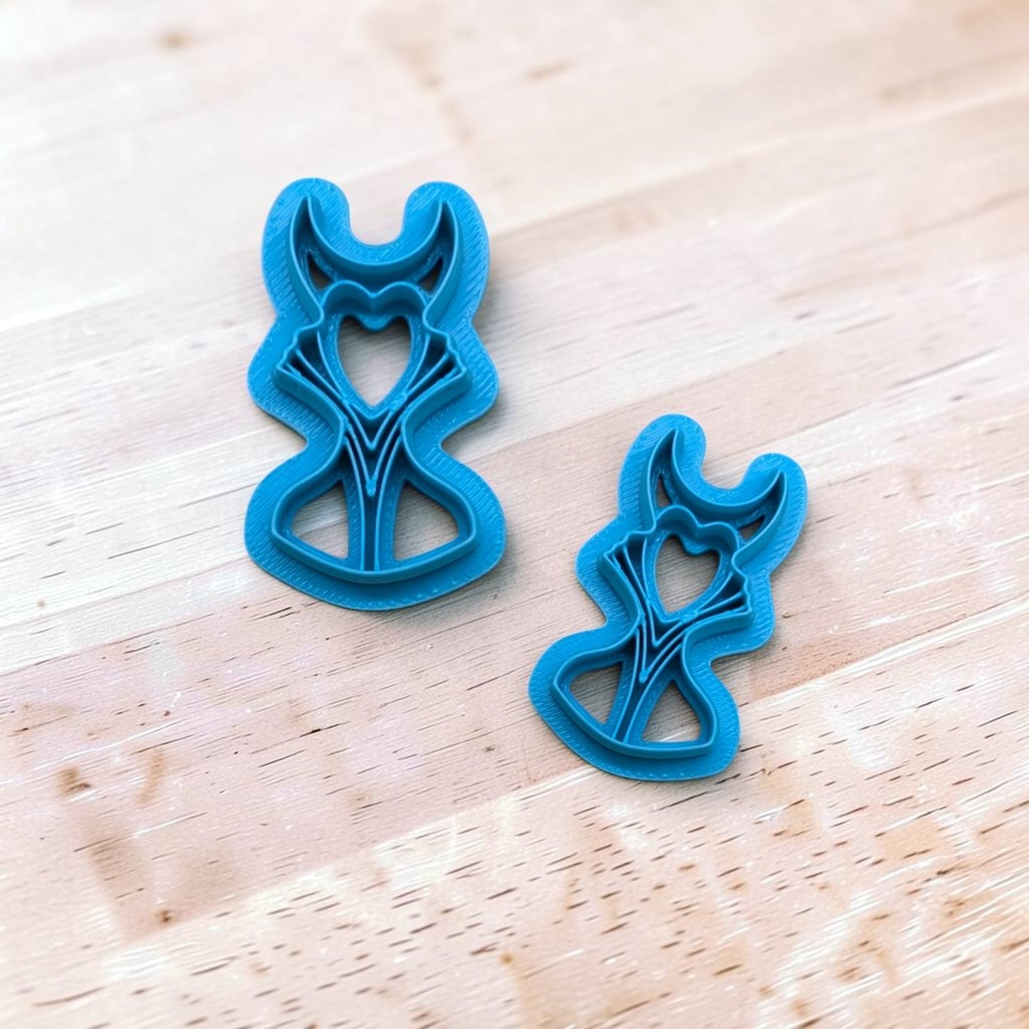 2 Blue plastic Maleficent shape cutters on a light wood surface