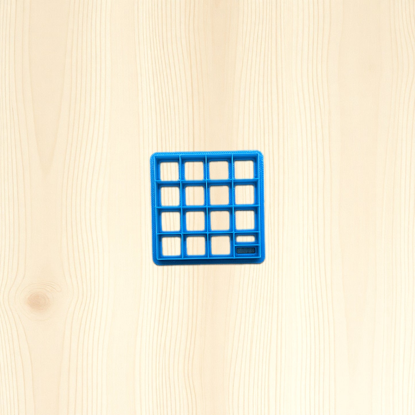Blue square tile cutter on a beige wooden surface