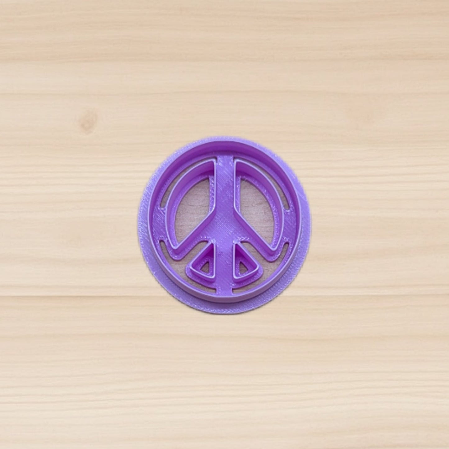 Purple peace sign cookie cutter on a wooden surface