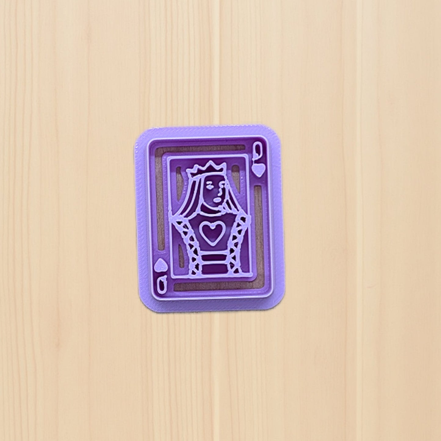 Purple Queen of Hearts playing card cookie cutter on a light wood background, featuring a crowned queen design with heart details—ideal for cookies, fondant, polymer clay, and pottery crafts.