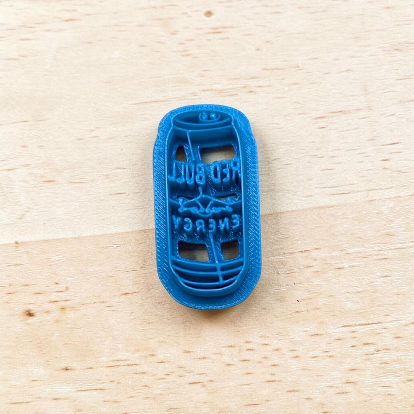 Blue 3D-printed object Slim Red Bull energy can cookie cutter on a wooden surface