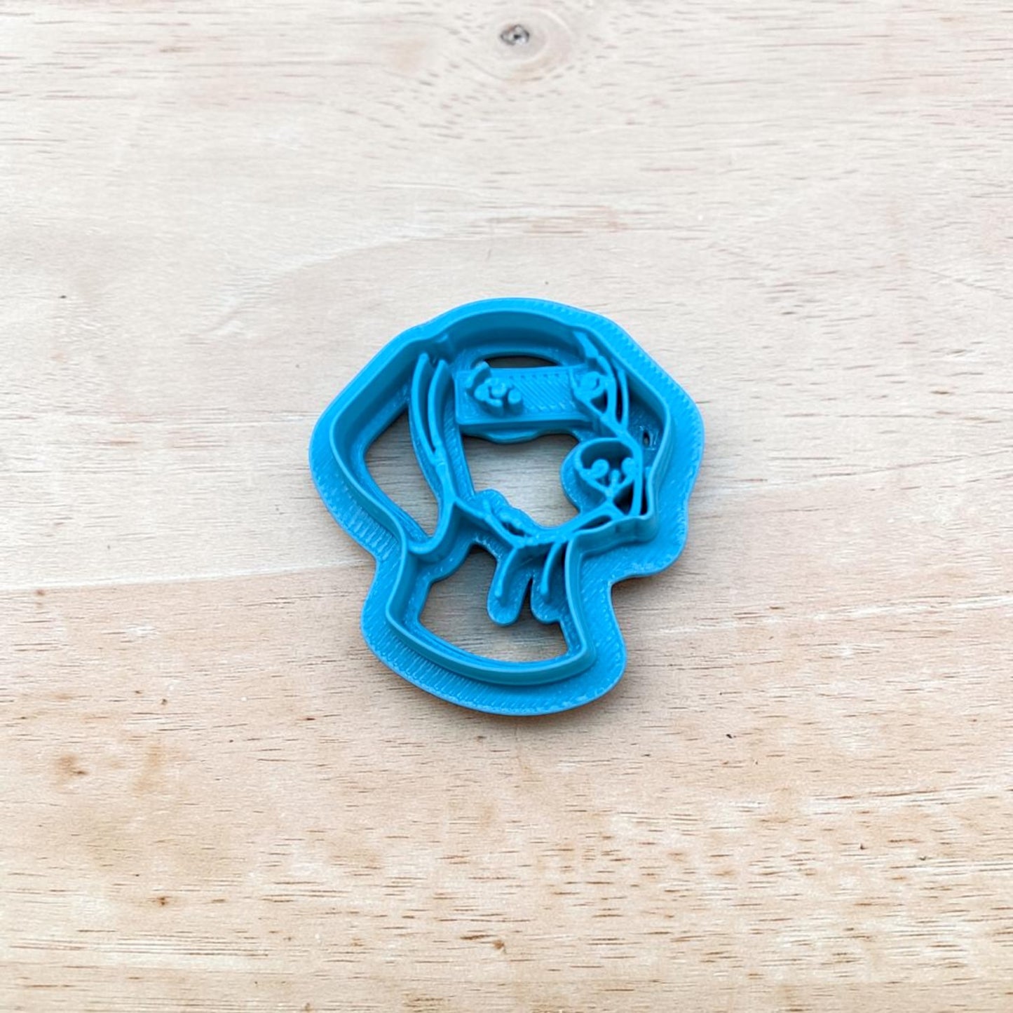 Blue cookie cutter shaped like a German shorthaired pointer dog on a wooden surface