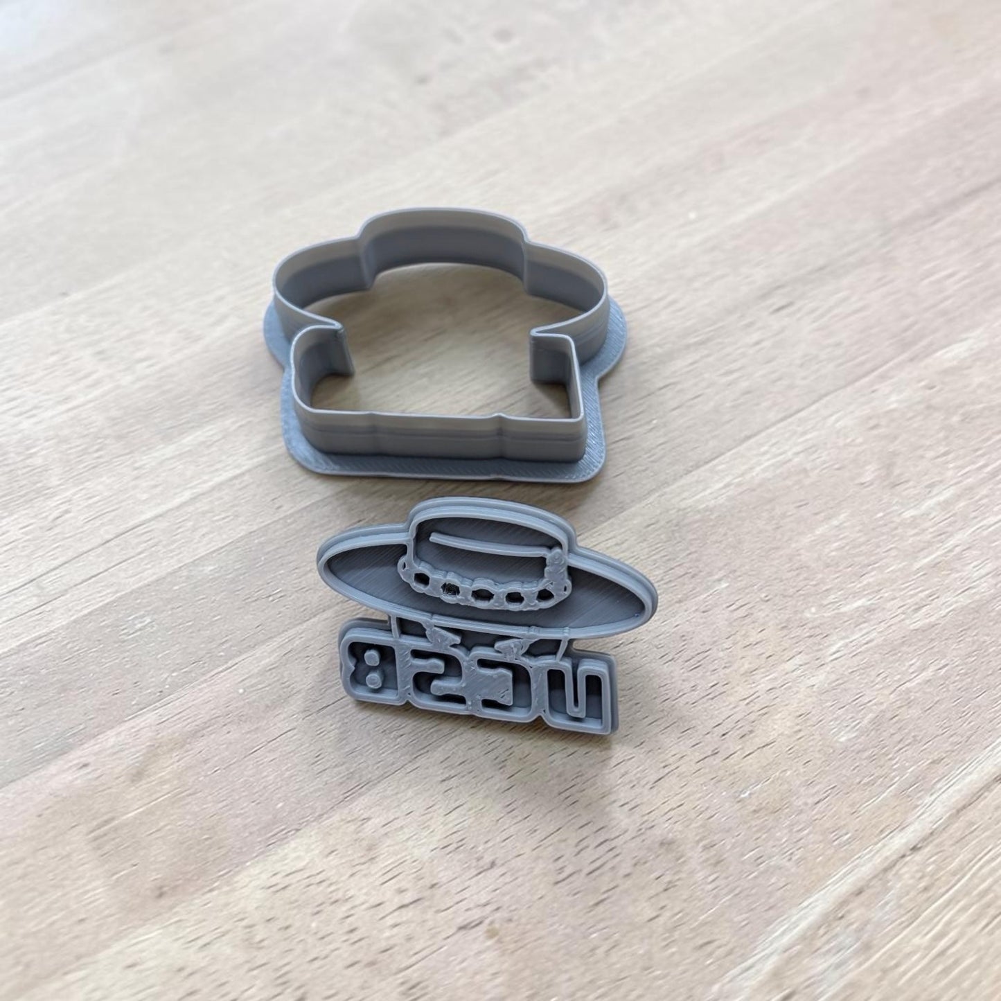 Two gray plastic cookie cutters on a light wood grain surface.