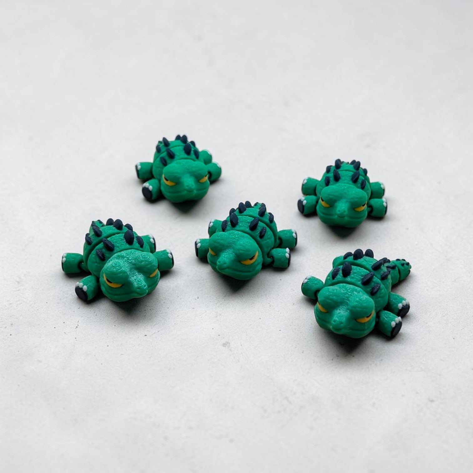Five Mini Flexi Alligator articulated desk buddy toys in green with navy spikes, handmade polymer clay reptile figurines on light gray background.