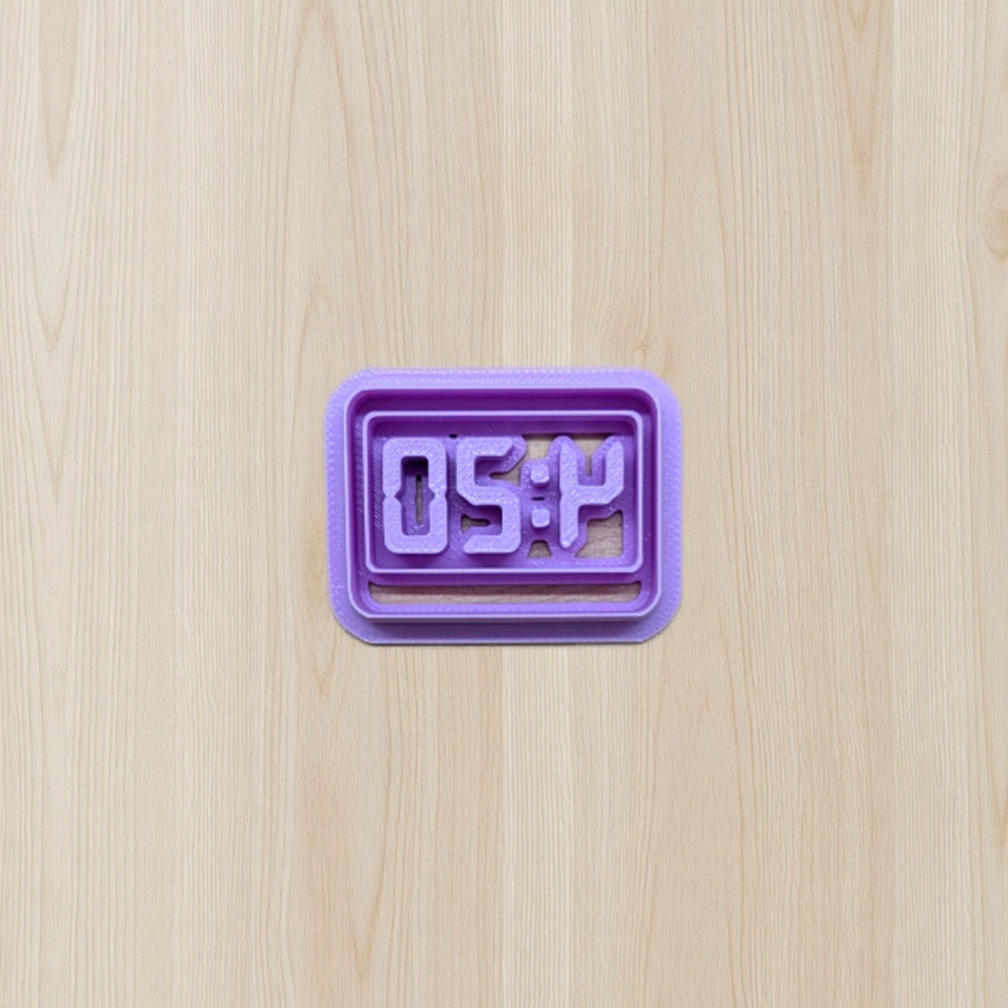 Purple digital clock cookie cutter displaying '4:20' time on a wooden surface
