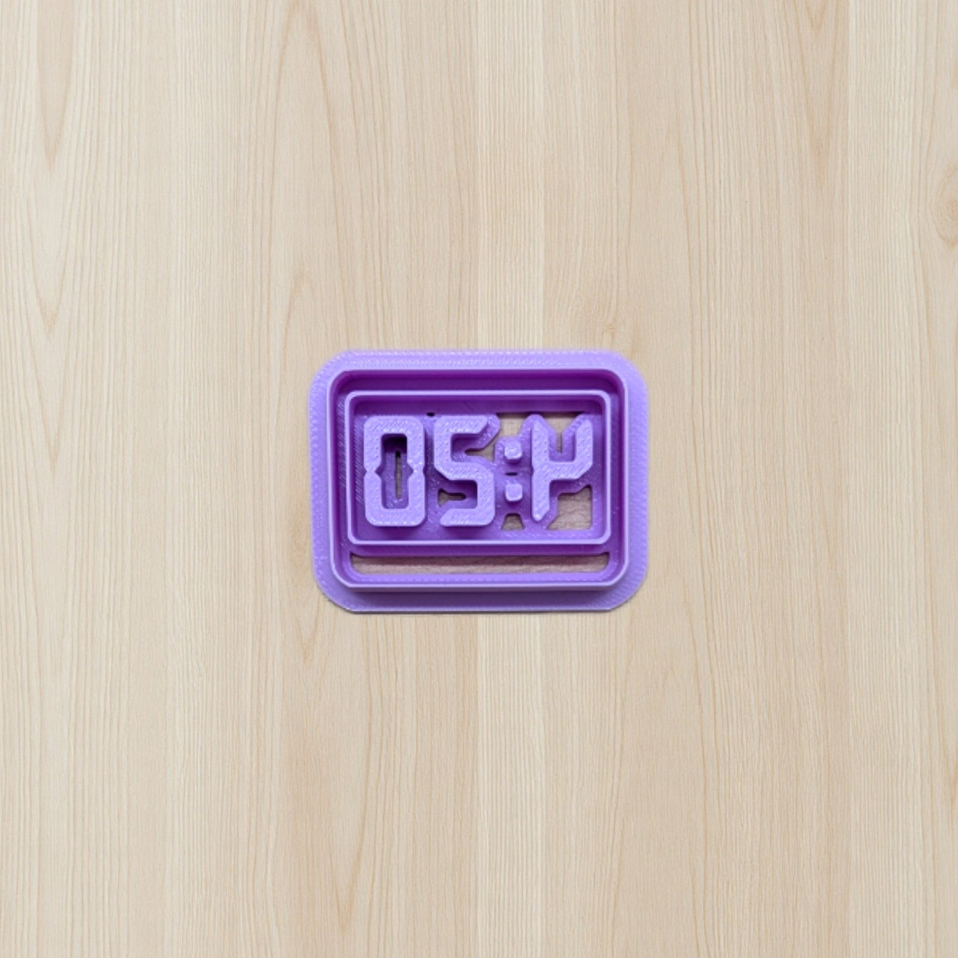 Purple digital clock cookie cutter displaying '4:20' time on a wooden surface