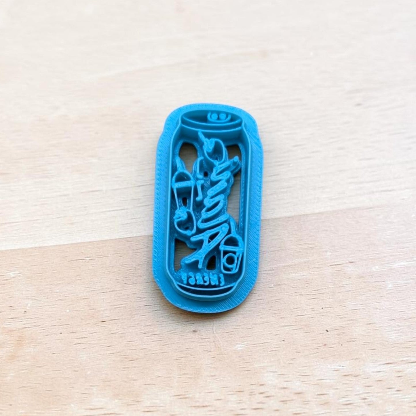 Blue 3D‑printed Alani Nu energy drink can cookie cutter on light wood background — perfect for cookies, fondant, and polymer clay.