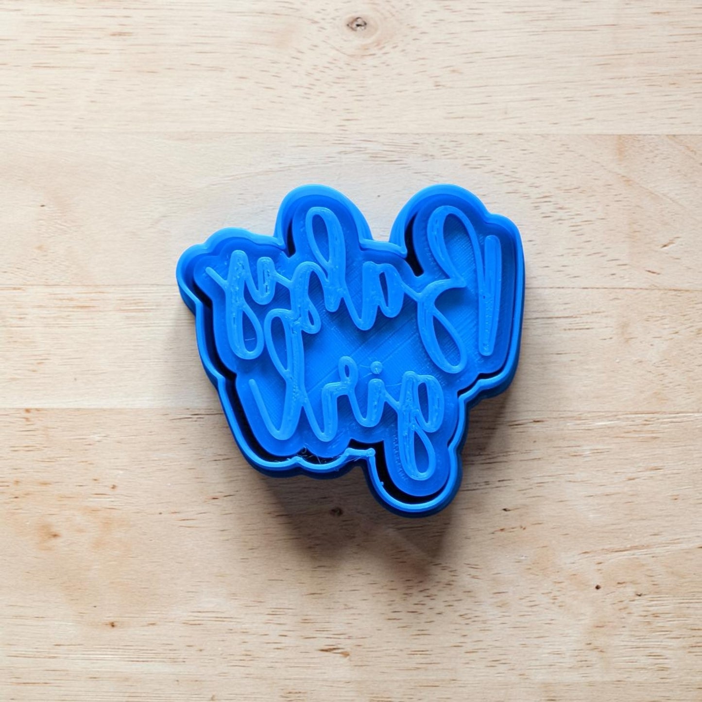 Blue cookie cutter with 'Baby girl' text on a wooden surface
