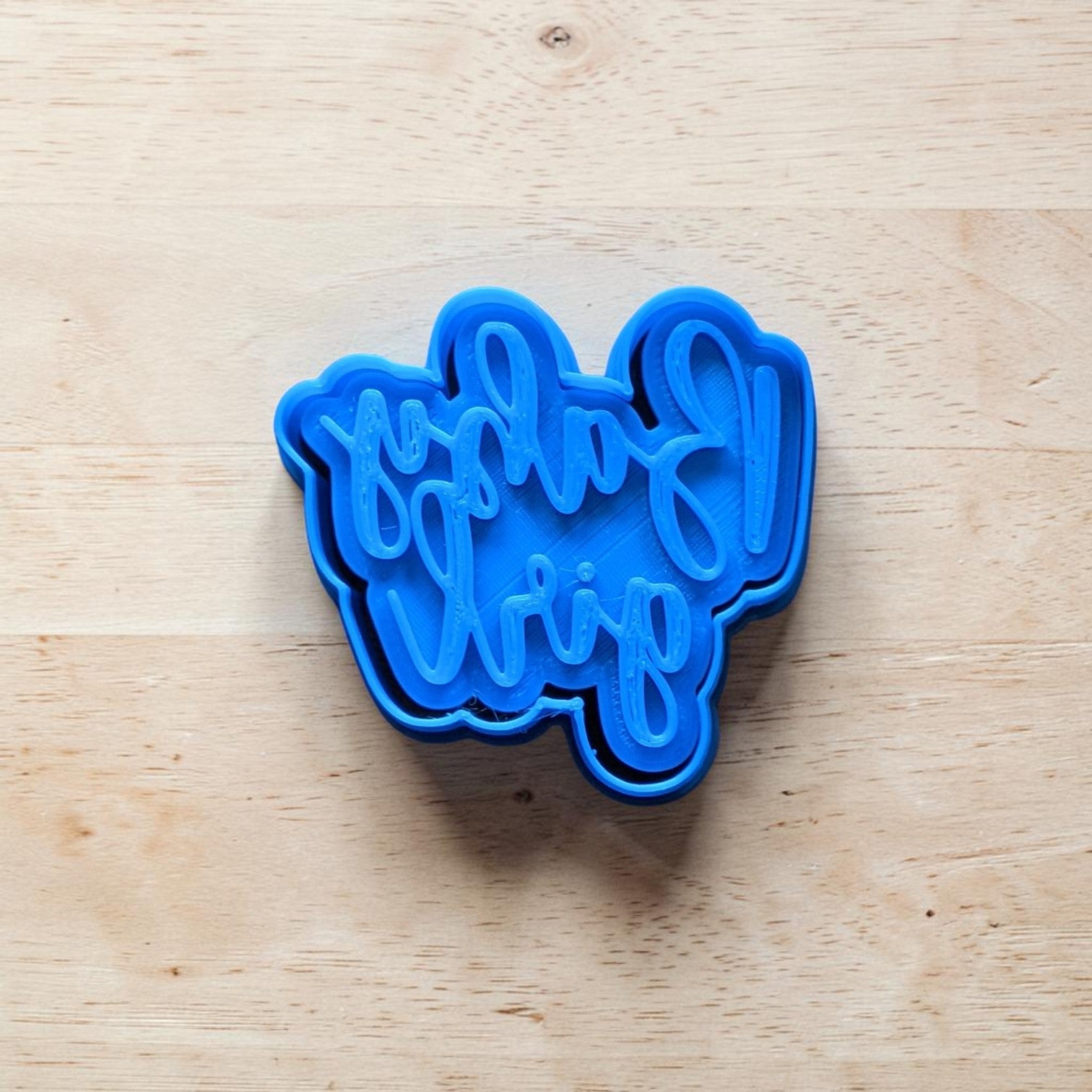 Blue cookie cutter with 'Baby girl' text on a wooden surface