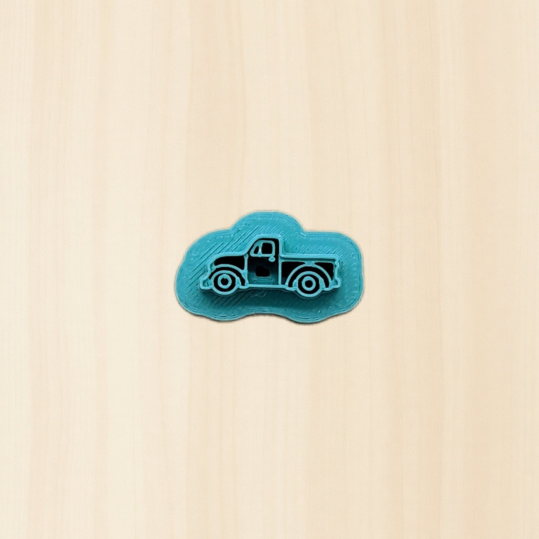Blue truck-shaped cookie cutter object on a wood background