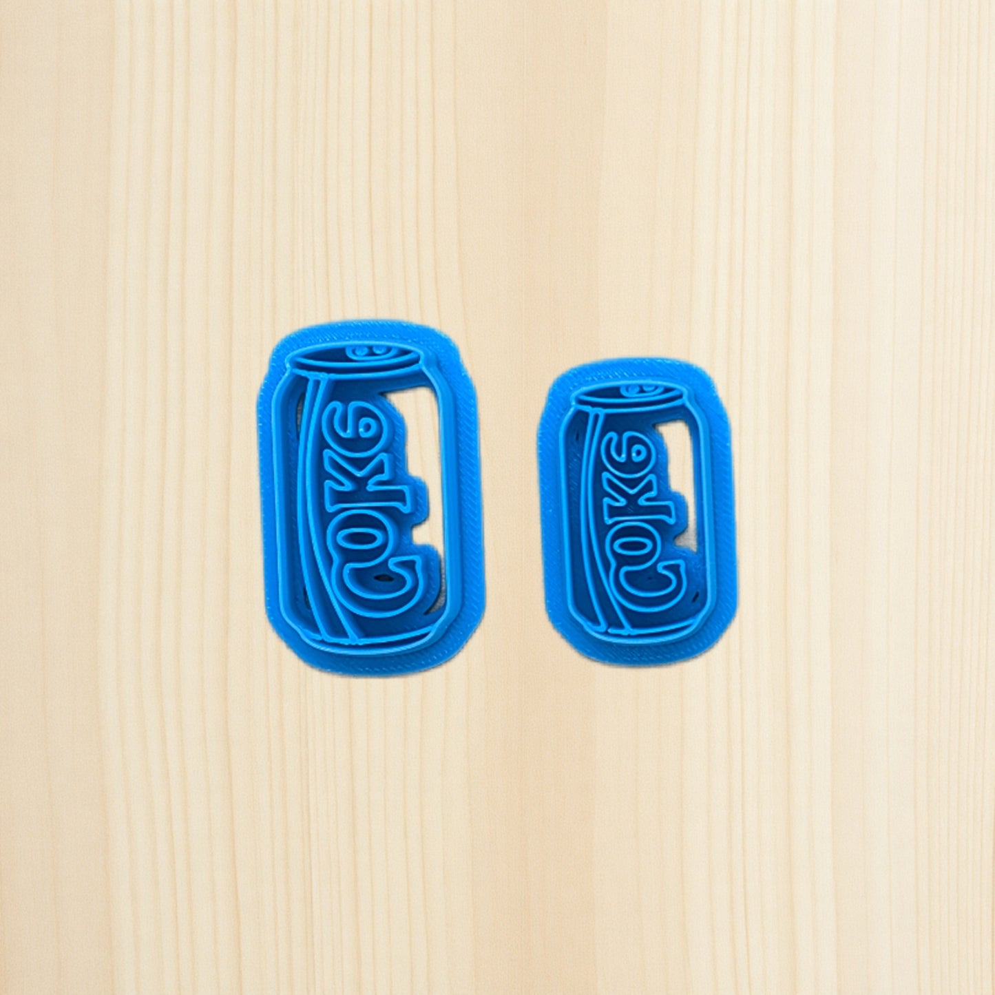 Two blue can-shaped cookie cutters on a beige background