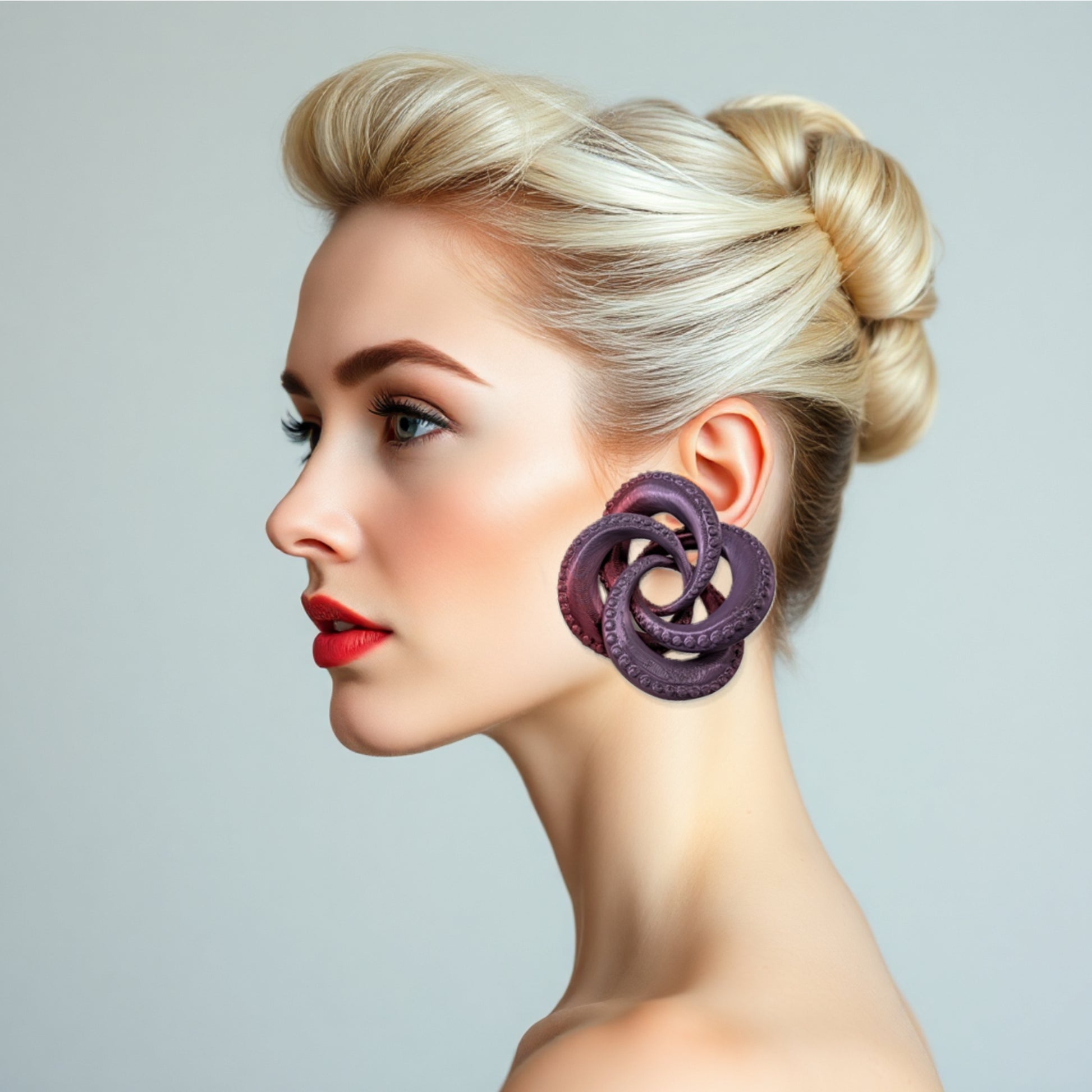 Woman wearing a large purple earring with a gray background