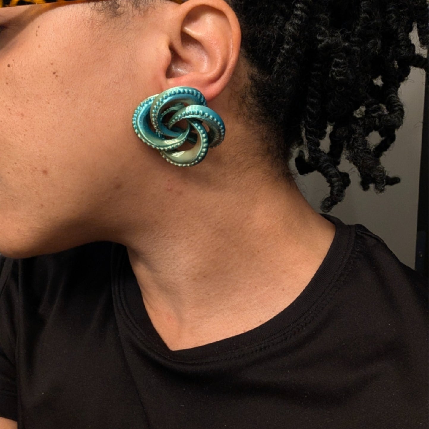 Close-up of a person wearing a large turquoise spiral earring.