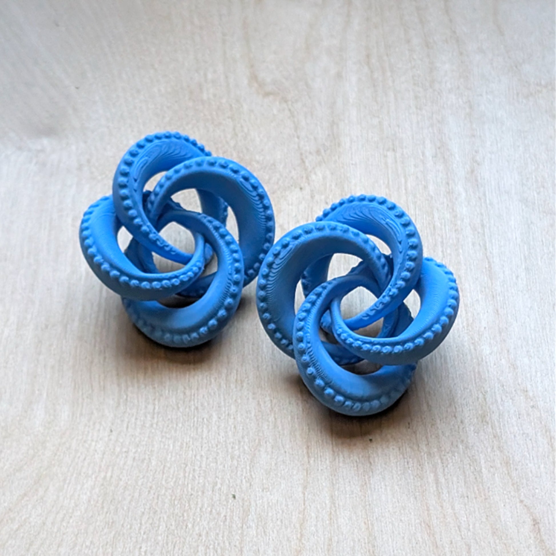 Blue knot-shaped objects on a light wooden surface