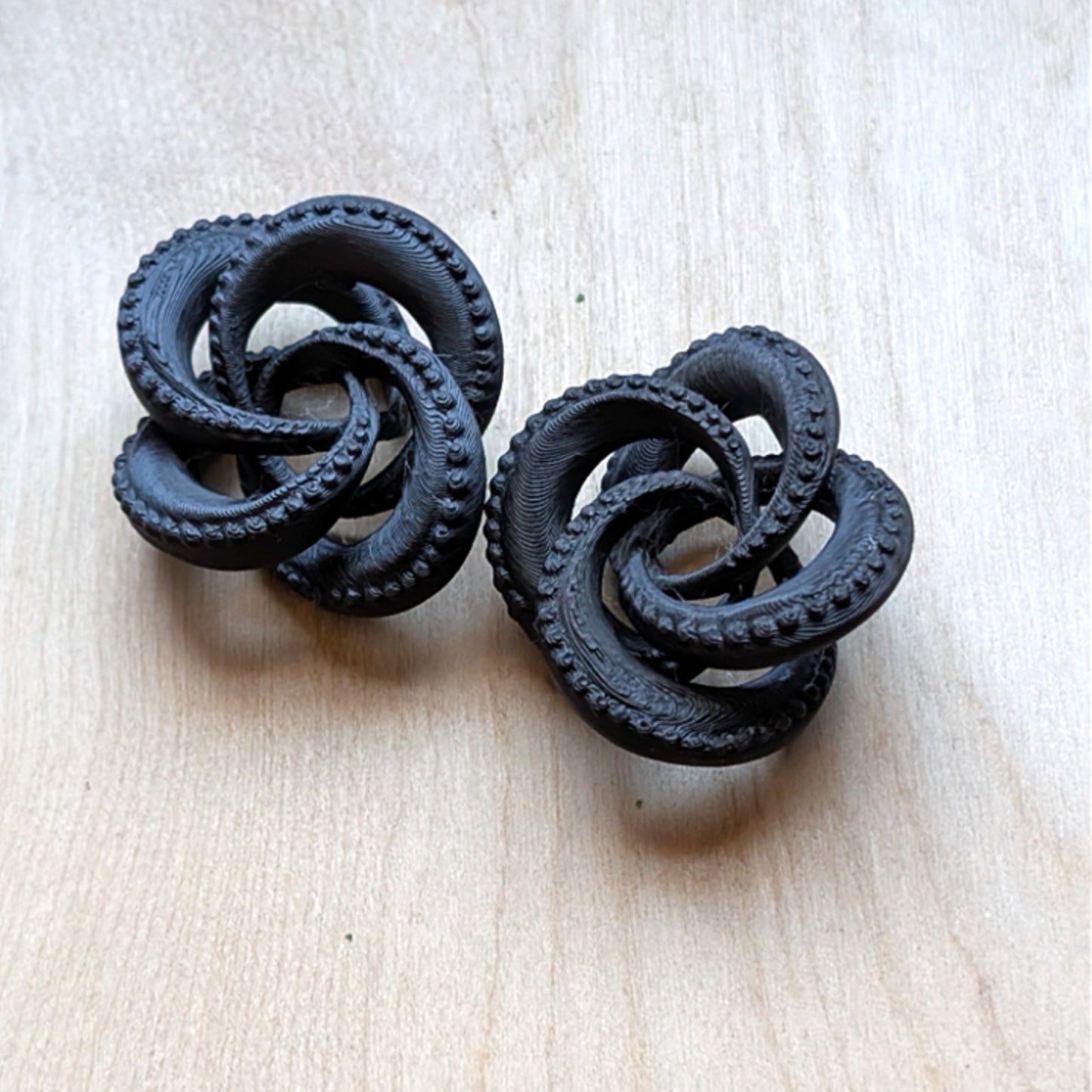 Pair of black knot earrings on a light beige background