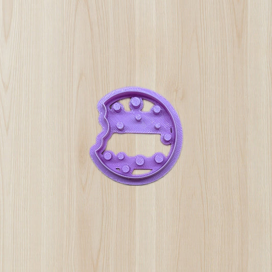 Purple cookie cutter shaped like a dinosaur on a wooden surface