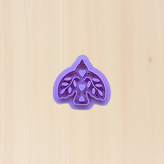 Purple boho bird cookie cutter with folk art design on a birchwood background
