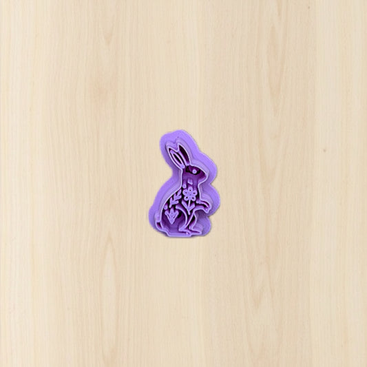 Purple bunny-shaped cookie cutter on a beige wooden surface