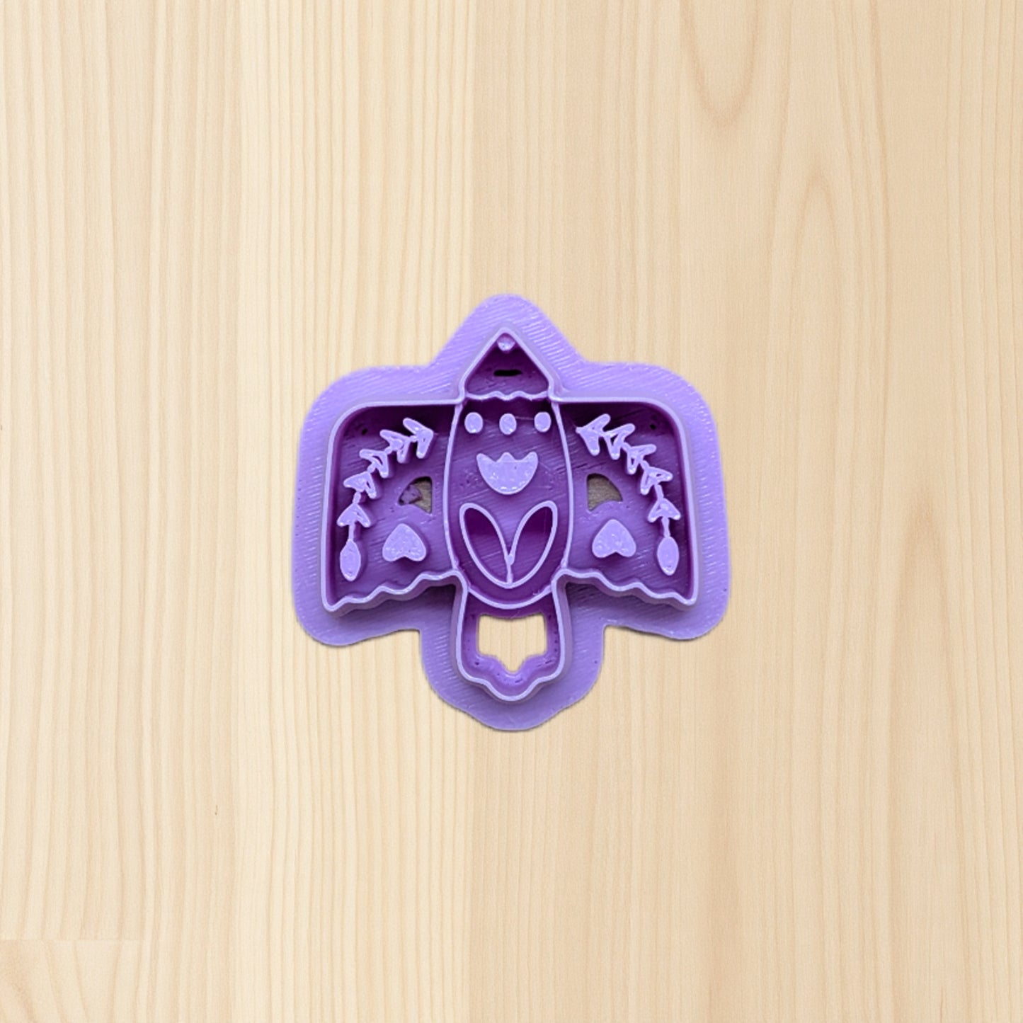 Purple boho folk art bird cookie cutter with bird design on a wooden surface