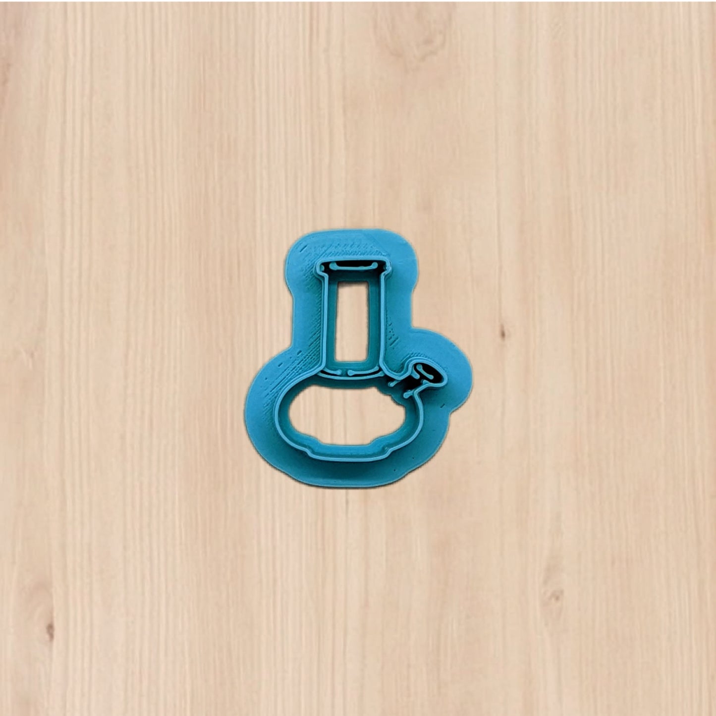 Plastic blue bong shape cookie cutter on a wooden surface