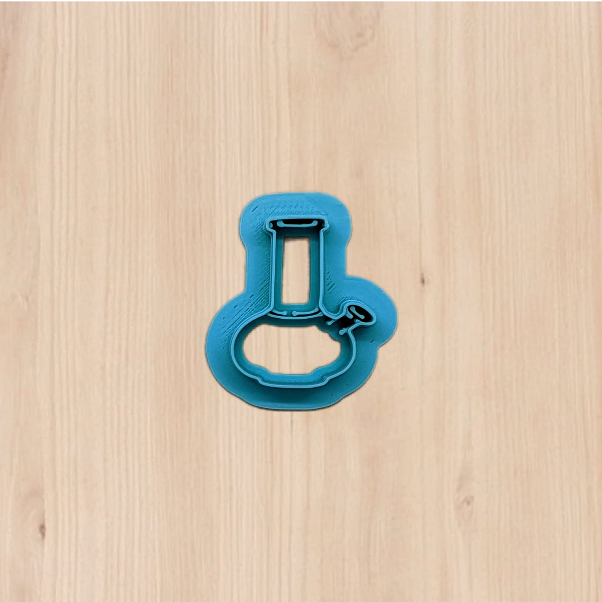 Plastic blue bong shape cookie cutter on a wooden surface