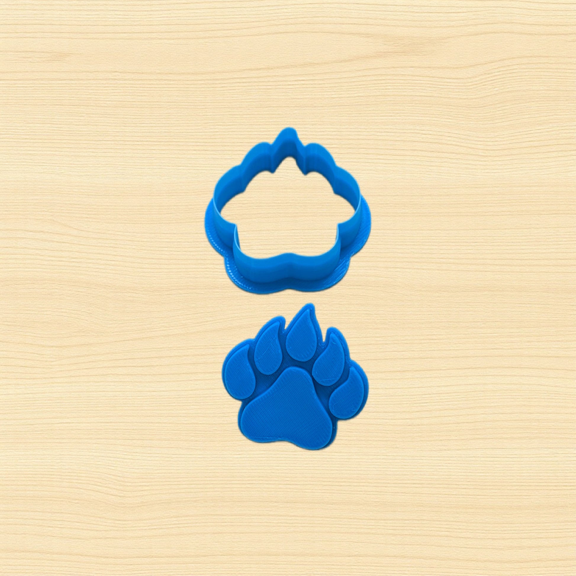 Blue paw print stamp and cookie cutter on a beige wooden surface