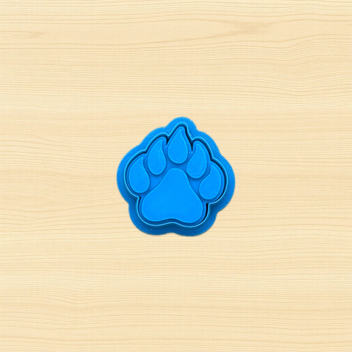 Blue paw print cookie cutter on a beige wooden surface