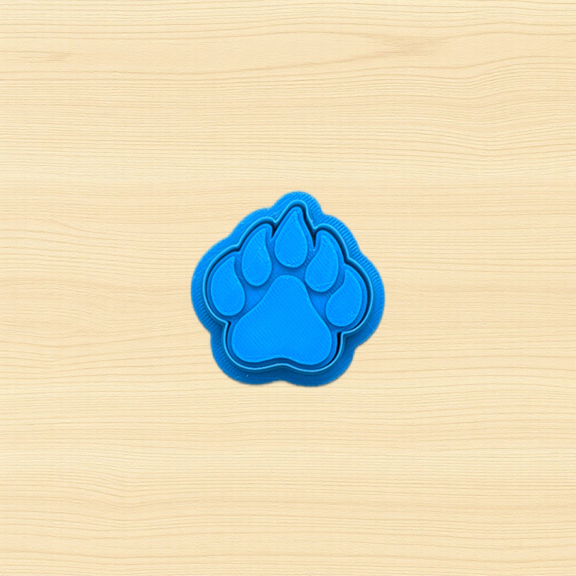 Blue paw print cookie cutter on a beige wooden surface