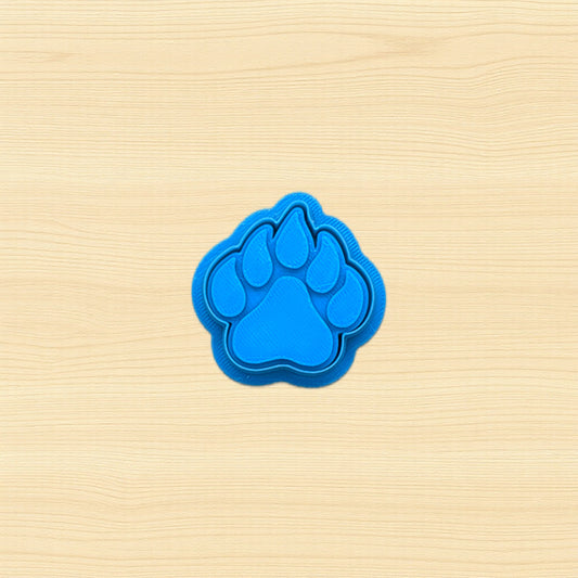 Blue paw print cookie cutter on a beige wooden surface