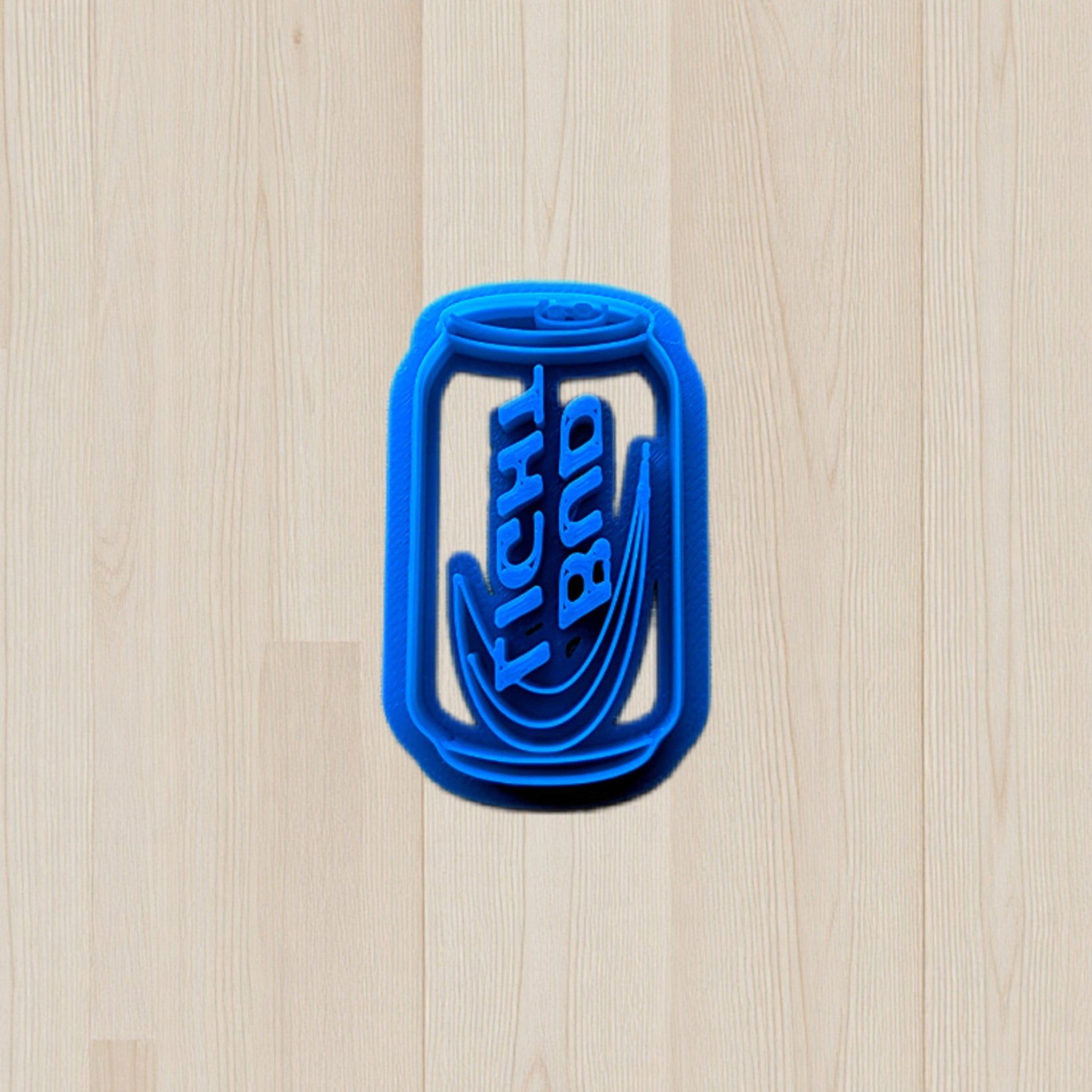 plastic Bud Light beer can cookie and clay cutter on light color wood surface.