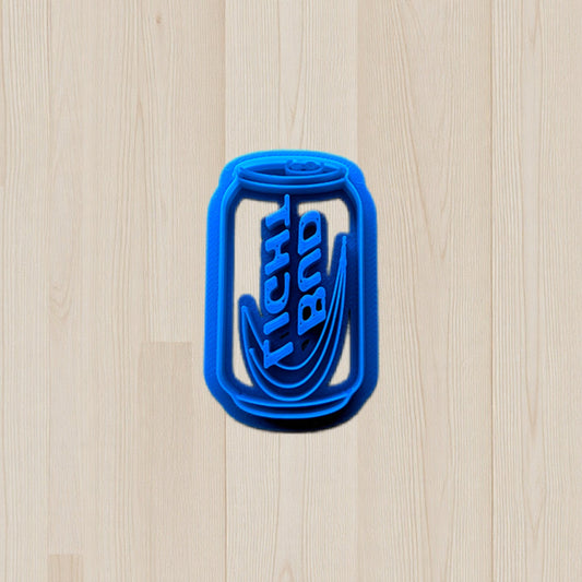 plastic Bud Light beer can cookie and clay cutter on light color wood surface.