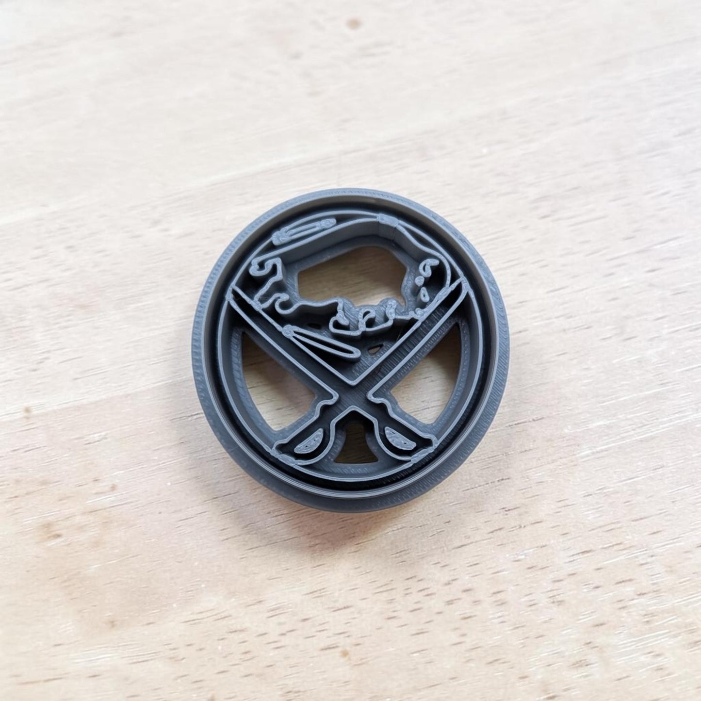 A plastic blue Buffalo Sabres cookie cutter design, resting on a light-colored wooden surface.