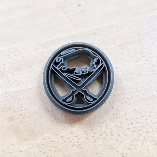 A plastic blue Buffalo Sabres cookie cutter design, resting on a light-colored wooden surface.
