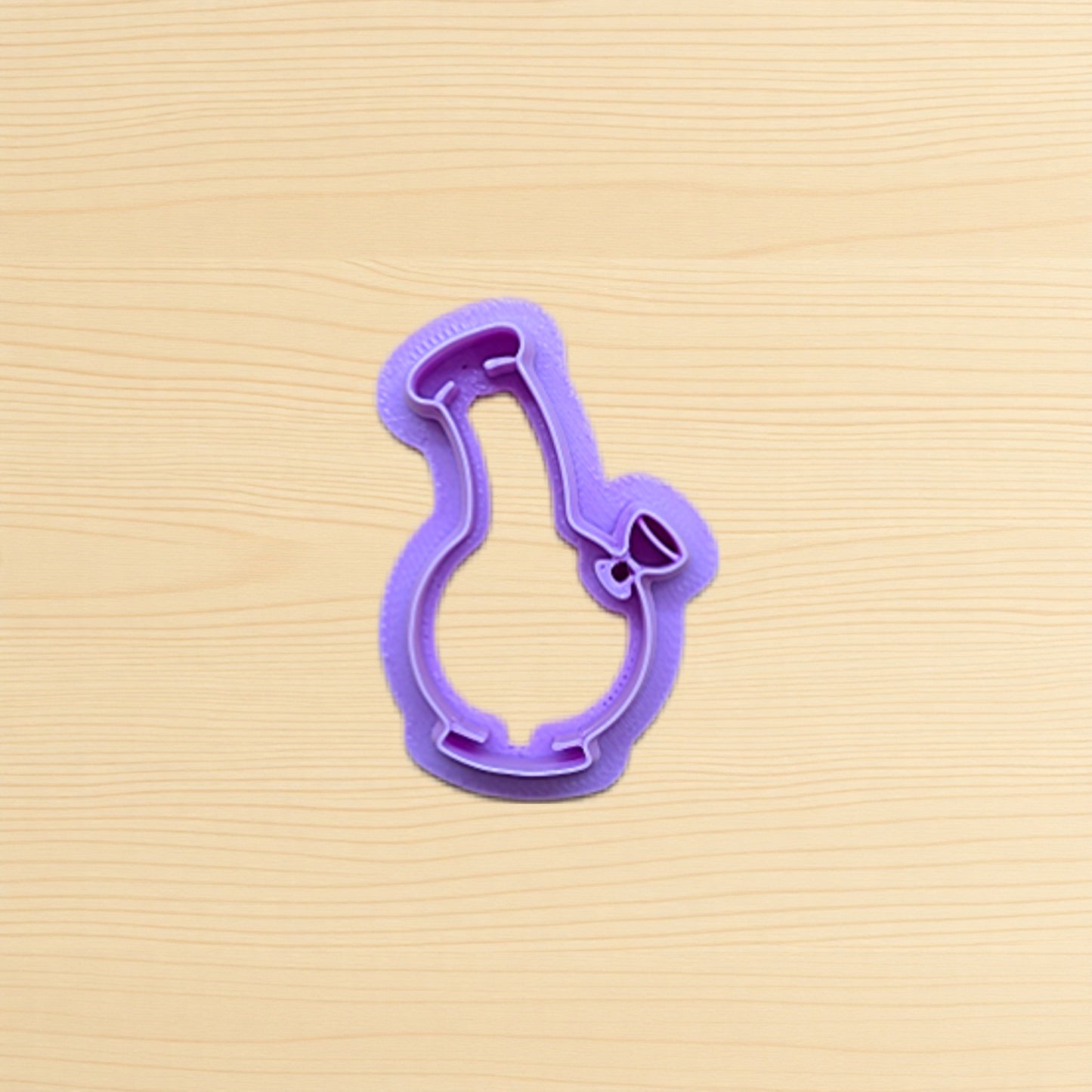 Purple cookie cutter shaped like a bong on a wood surface