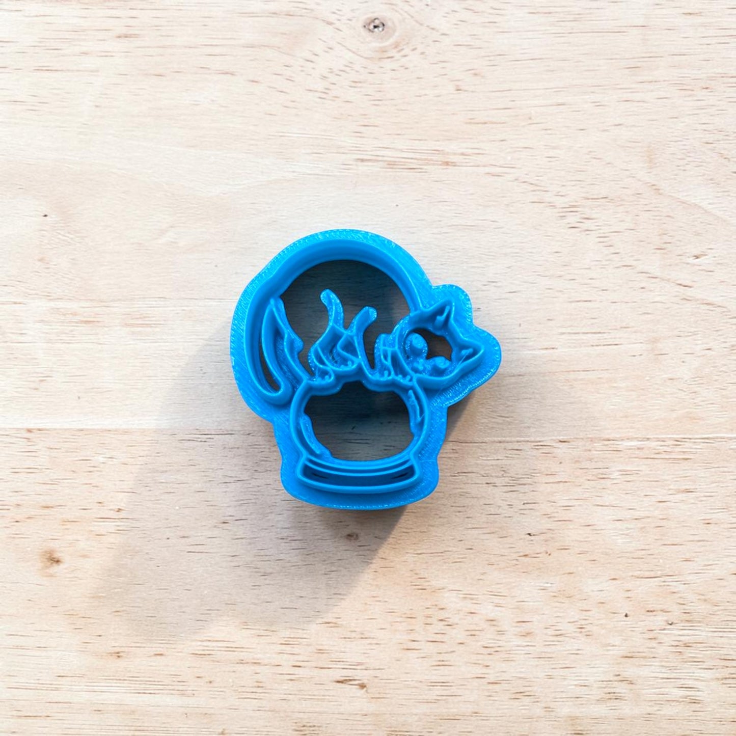 Blue cookie cutter shaped like a cat on a wooden surface