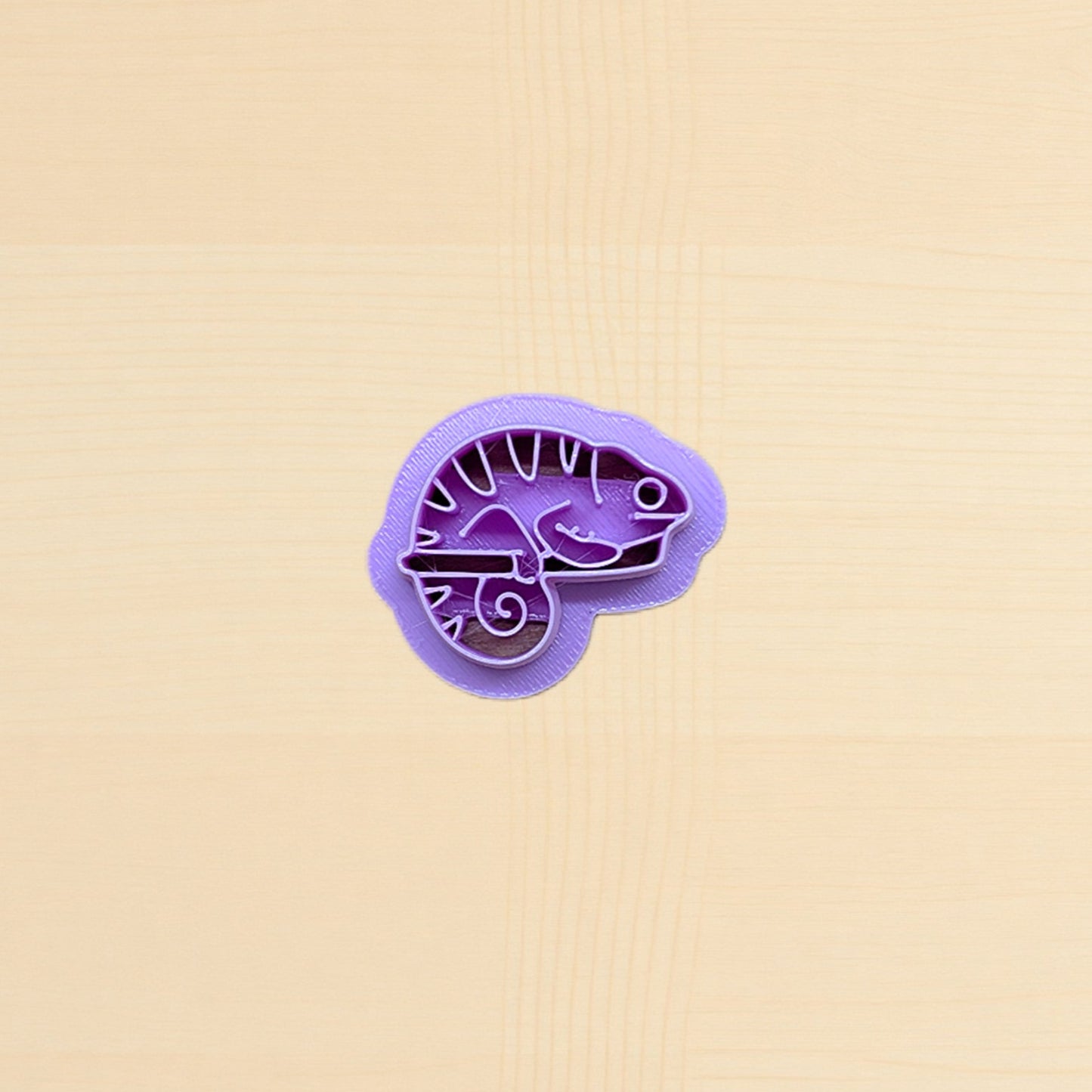 Purple lizard-shaped cookie cutter on a beige background