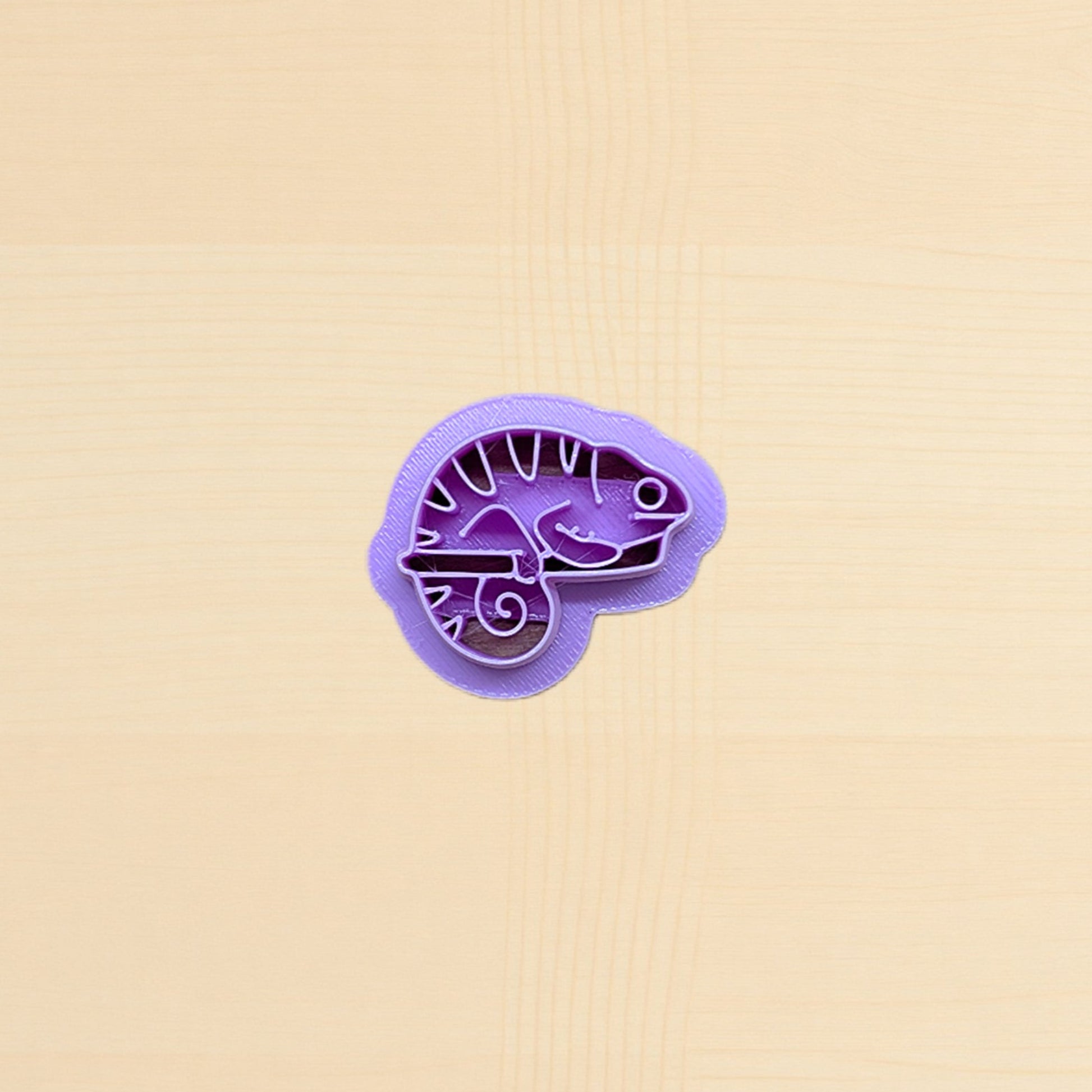 Purple lizard-shaped cookie cutter on a beige background