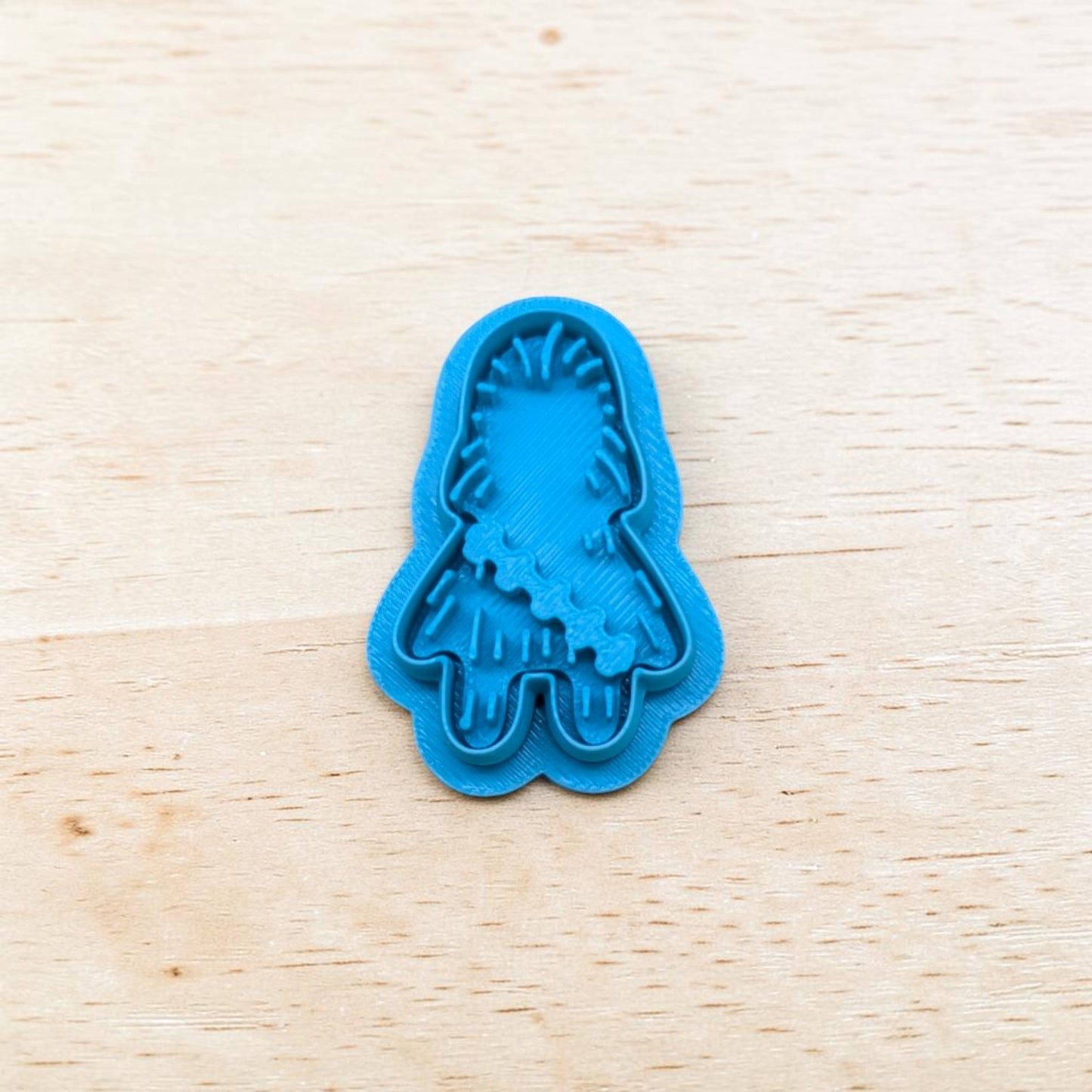 Plastic blue Chewbacca shaped cookie cutter on a light color wood surface.
