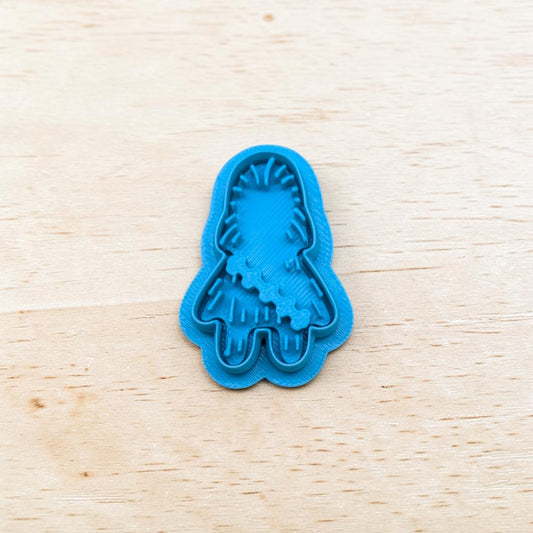 Plastic blue Chewbacca shaped cookie cutter on a light color wood surface.