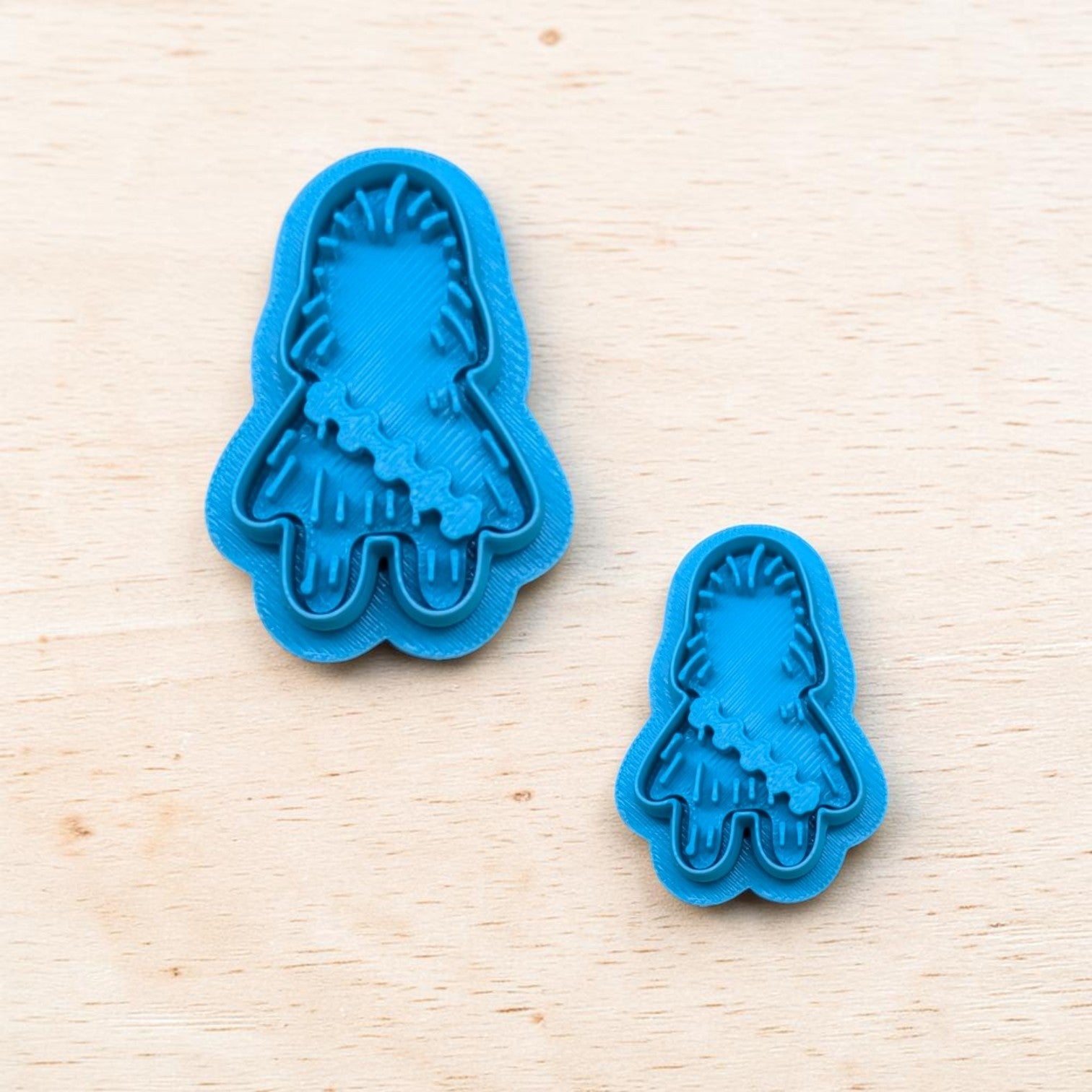 Plastic blue Chewbacca shaped cookie cutters on a light color wood surface.