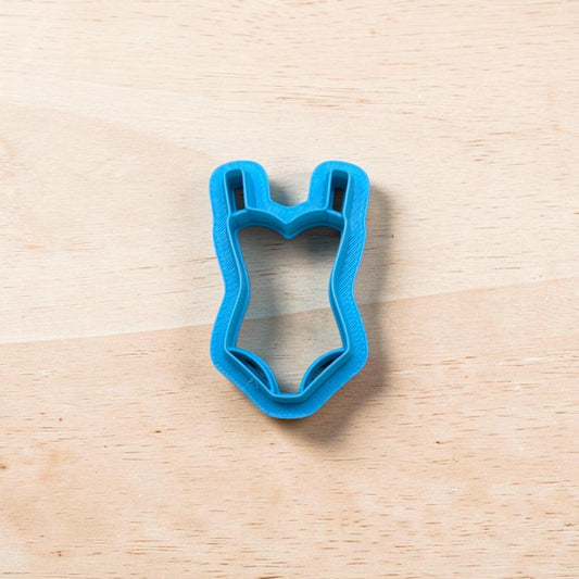 Blue swimsuit-shaped cookie cutter on a wooden surface