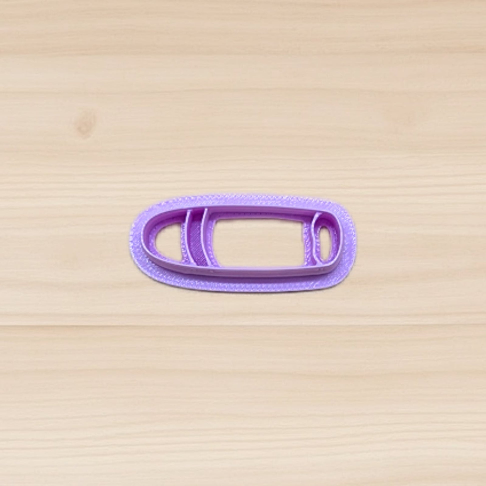 Purple cigar shape cookie cutter on a wooden surface