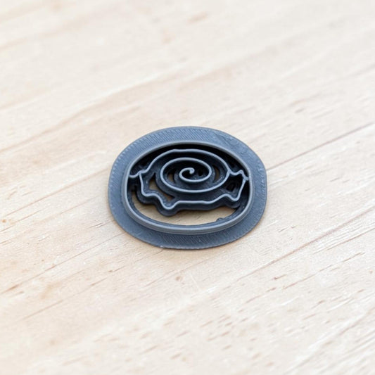 Cinnamon roll cookie cutter with spiral swirl design and smooth rounded edges, displayed on a light wooden surface—perfect for cookies, fondant, polymer clay, and pottery crafts.