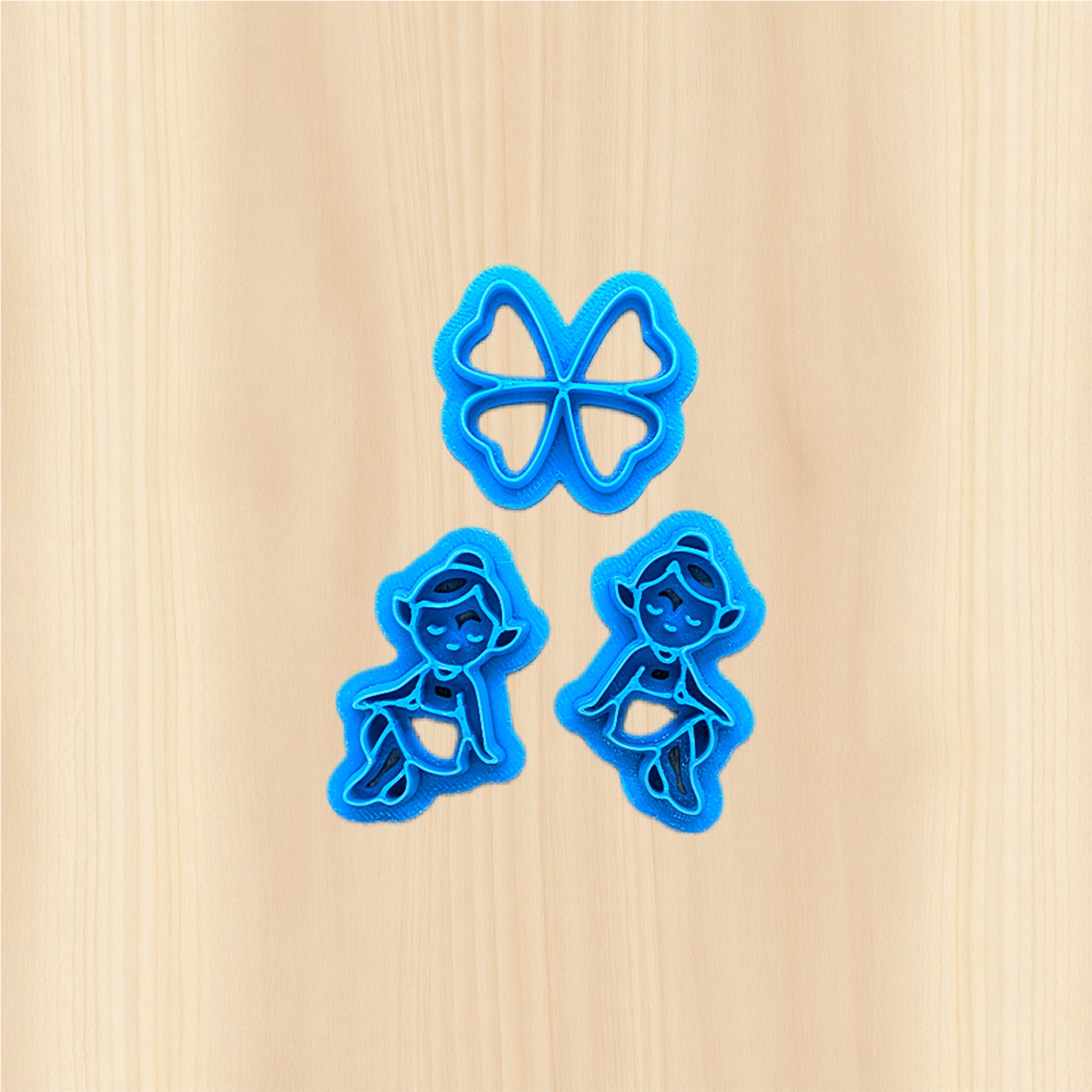 St. Patrick's Day Clover Fairy and wings cookie cutters on a wooden surface.