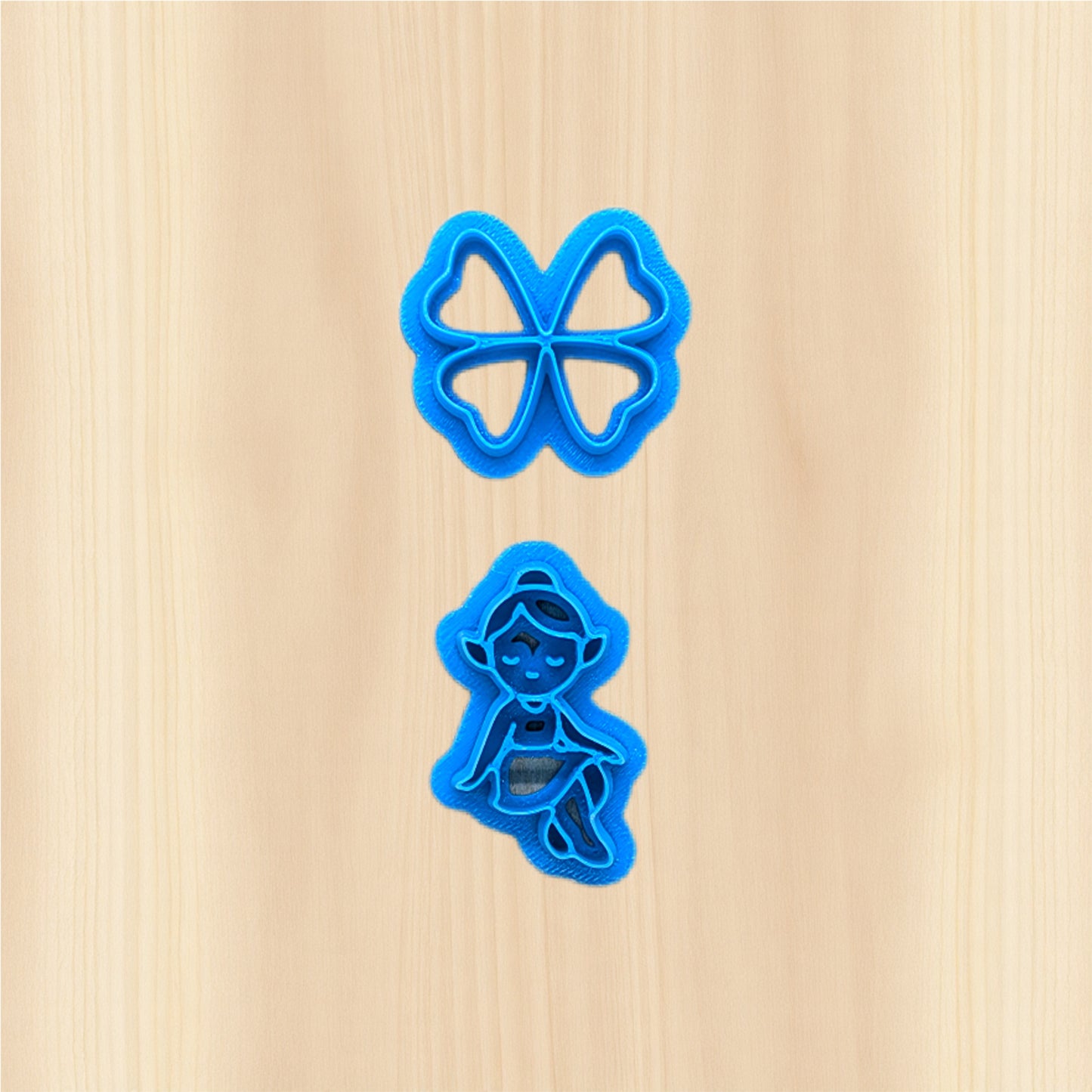 St. Patrick's Day Clover Fairy and wings cookie cutters on a wooden surface.